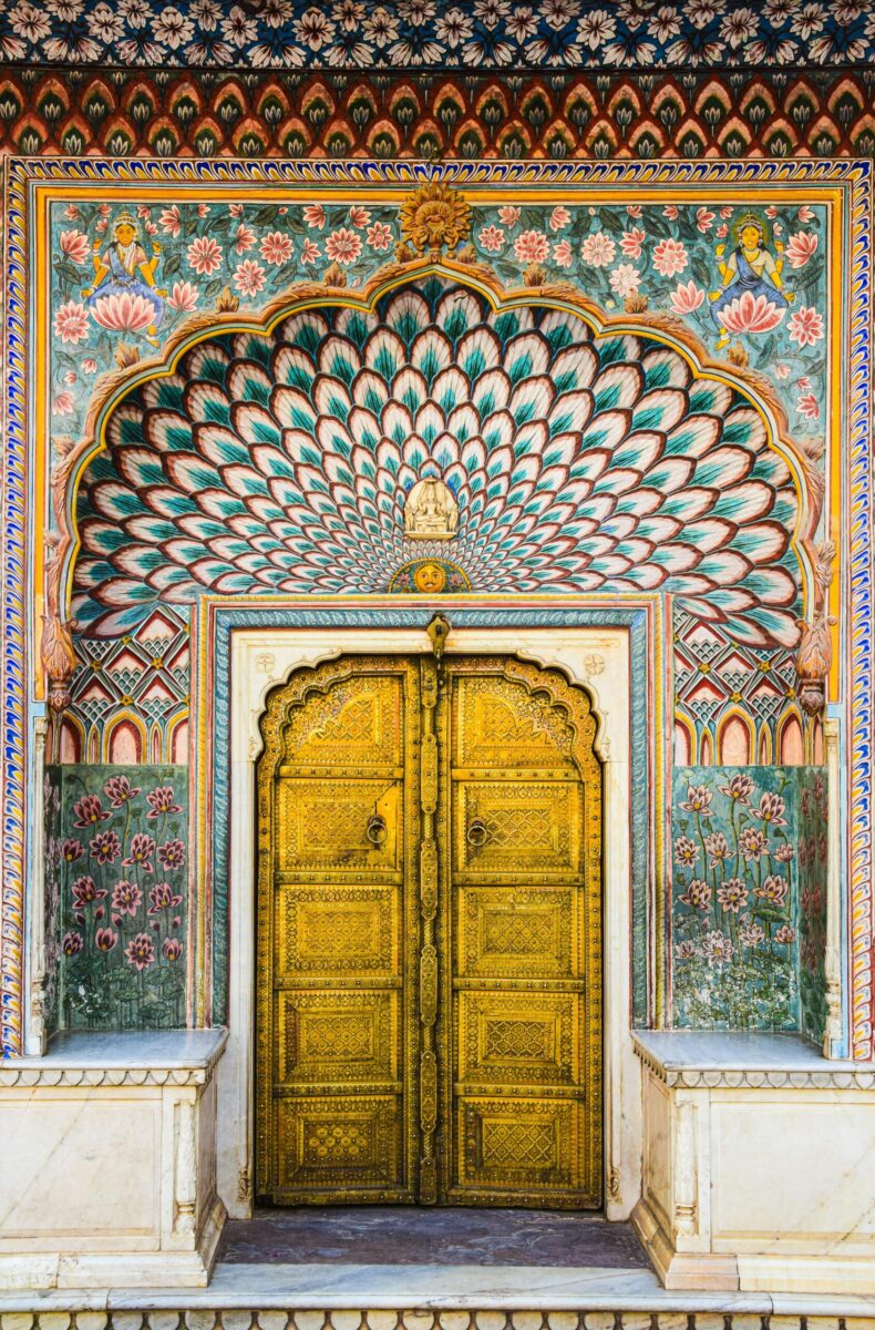 Intricate Mughal architecture at Jaipur's City Palace, showcasing vibrant peacock patterns and gold detailing.